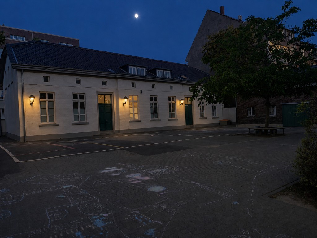 Katholische Grundschule Niederkassel – Schulhof und Schulgebäude bei Nacht mit Mond (Catholic primary school Niederkassel – schoolyard and building at night with moon)